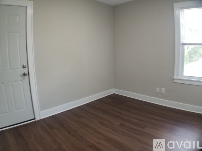 A room with a white door and wooden flooring.