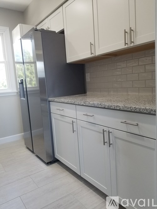A kitchen with a black fridge and white cabinets.