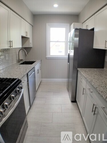 A kitchen with white cabinets and a black refrigerator.