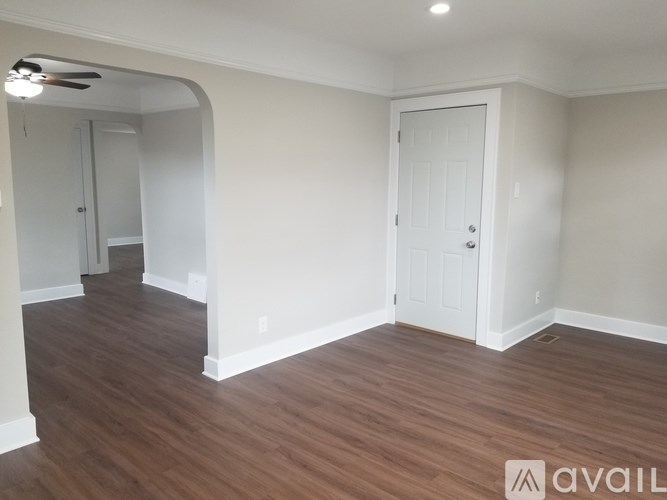 A room with a white door and a fan on the ceiling.