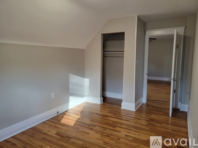 A room with wooden floors and white walls, with a doorway leading to another room.