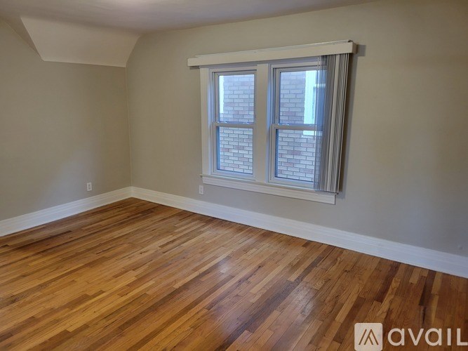 A room with wooden flooring and a window with blinds.