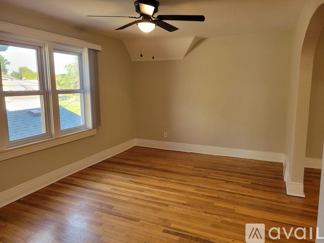 A room with a ceiling fan and wooden flooring.