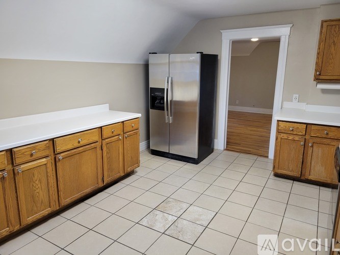 A kitchen with a refrigerator and wooden cabinets.
