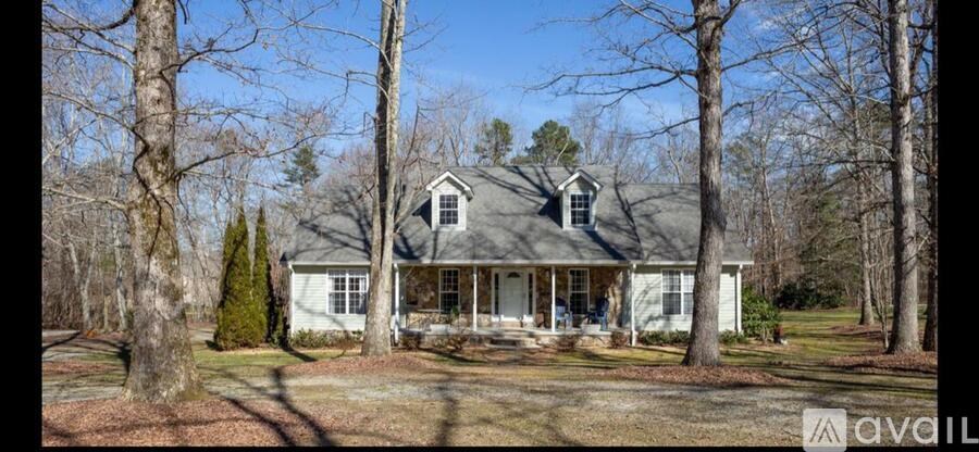 A house with a porch surrounded by trees.