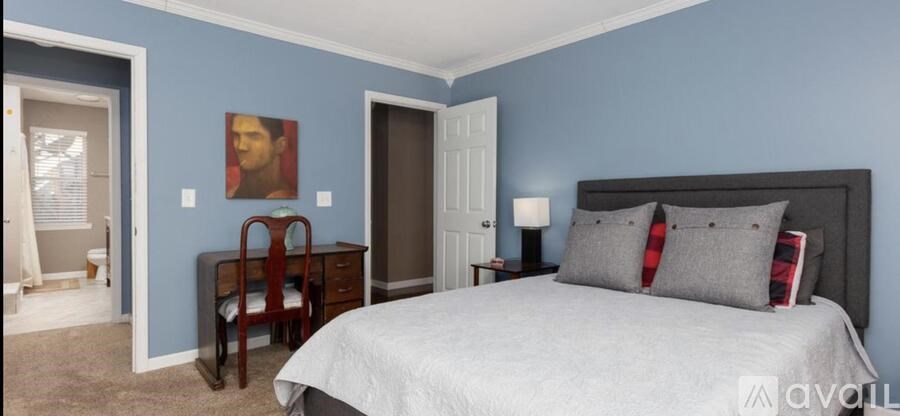 A bedroom with a bed, nightstand, and chair.