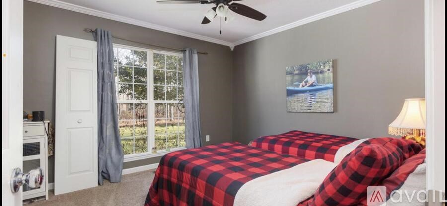 A bedroom with a red and black checkered bedspread.