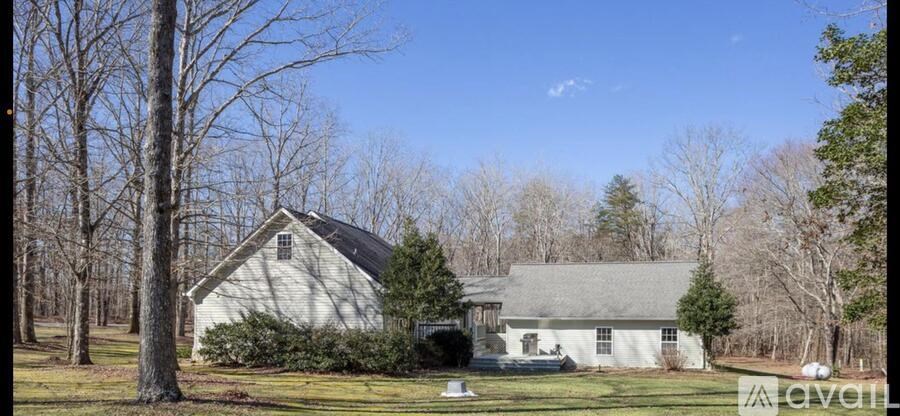A white house with a grey roof is surrounded by bare trees.