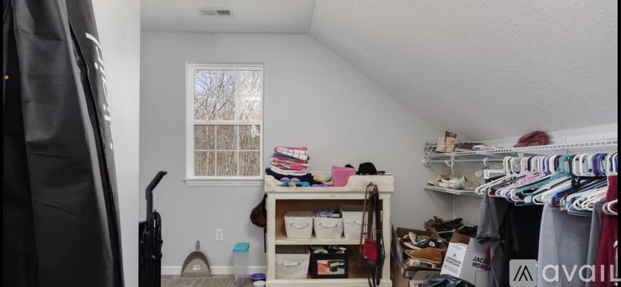 A room with a clothing rack and a vacuum cleaner.