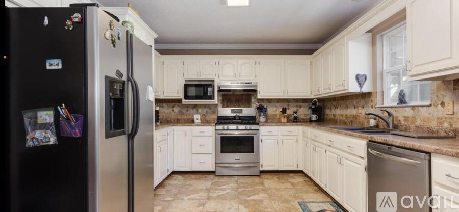 A kitchen with white cabinets and a black fridge.