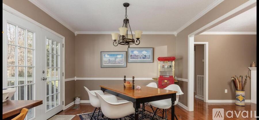 A dining room with a wooden table and white chairs.