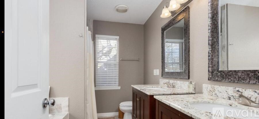 A bathroom with a toilet, sink, and mirror.