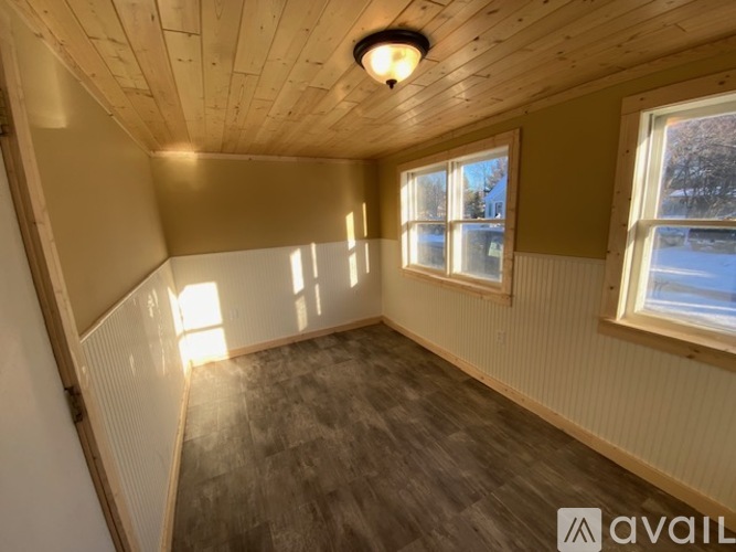A room with wooden walls and a window showing a snowy landscape outside.
