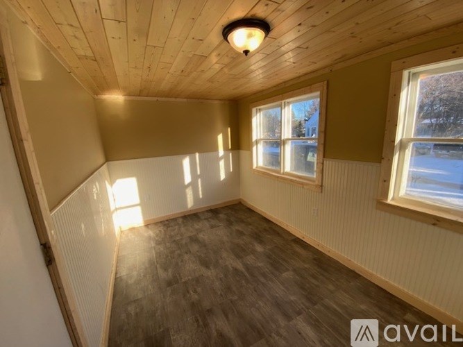 A room with wooden walls and a window showing a snowy landscape outside.