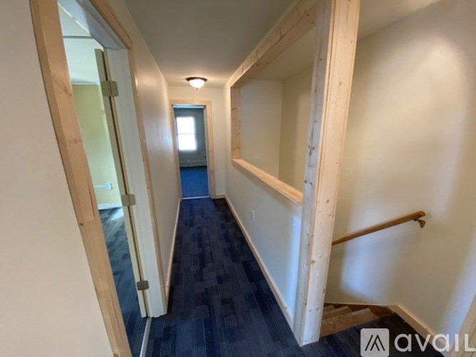 A hallway with a blue carpet and white walls.