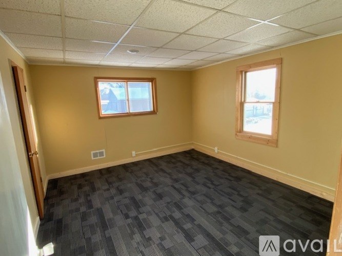 A room with a carpeted floor and two windows.