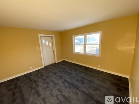 A room with a carpeted floor, a window, and a door.