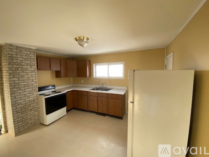 A kitchen with a refrigerator, sink, and cabinets.