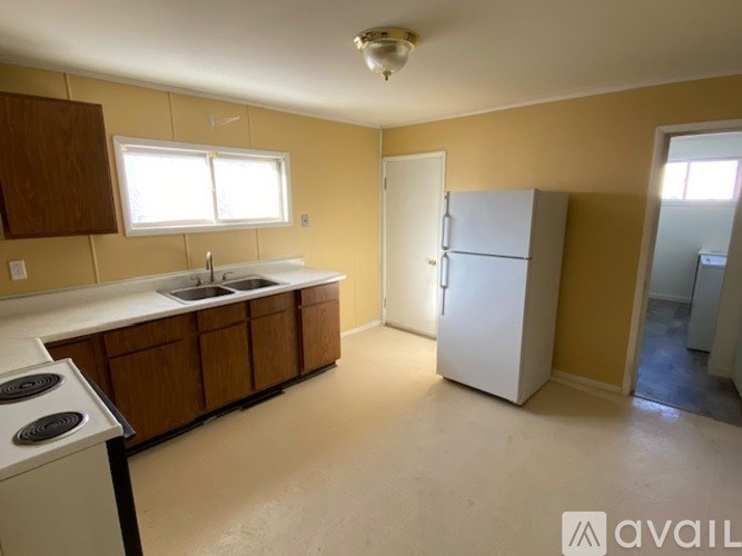 A kitchen with a stove, sink, and refrigerator.