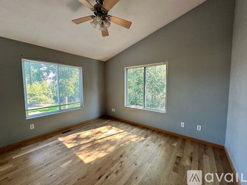 A room with wooden flooring and a ceiling fan.