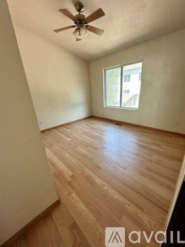 A room with wooden flooring and a ceiling fan.