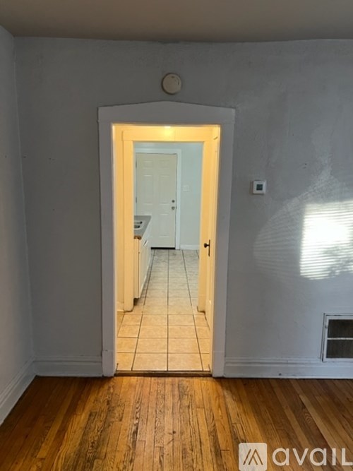 A room with a wooden floor and a doorway leading to another room.
