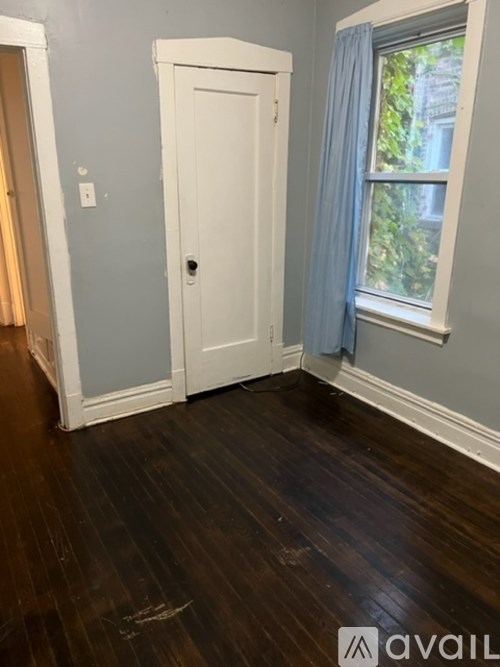 A room with a white door and a window with blue curtains.