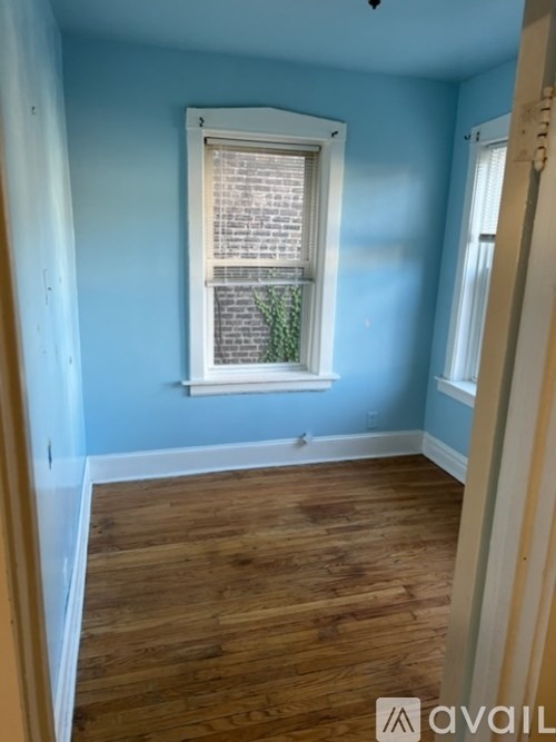 A room with wooden floors and a window with a plant in it.