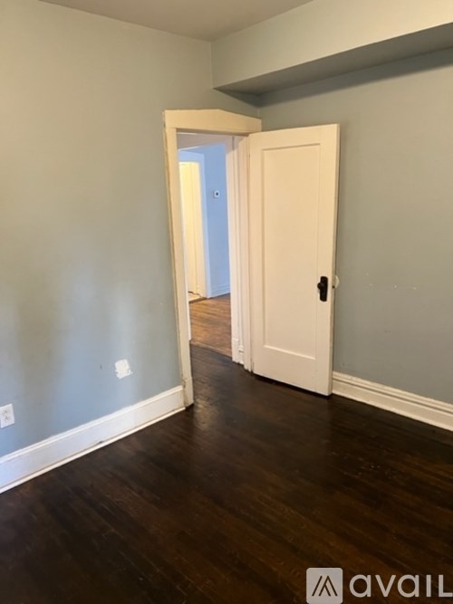 A room with a white door and wooden floor.