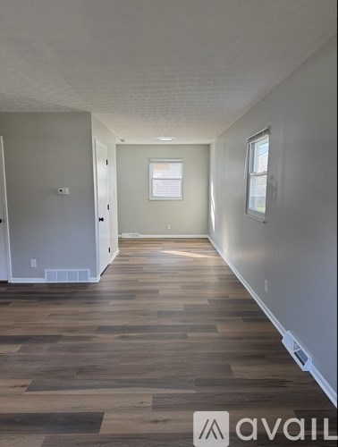 A long hallway with wood floors and a window.