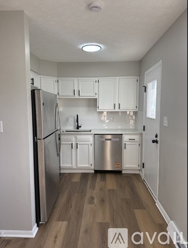 A kitchen with white cabinets and a wooden floor.