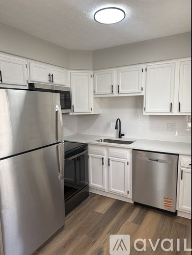 A kitchen with white cabinets and a stainless steel refrigerator.