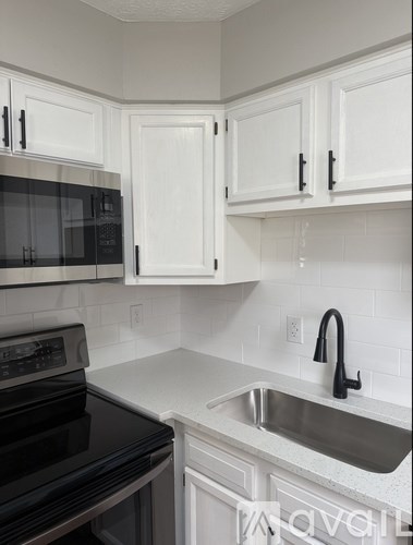 A kitchen with white cabinets and a black stove top oven.