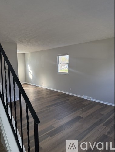 A room with wooden flooring and a window with blinds.