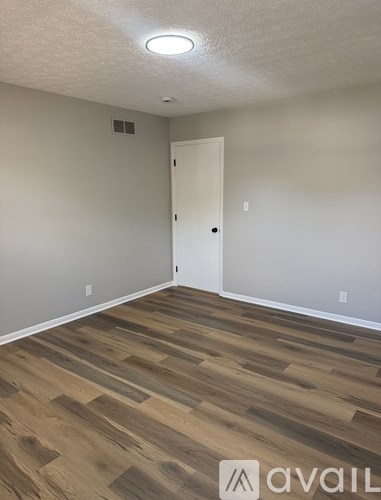 A room with wooden flooring and a white door.