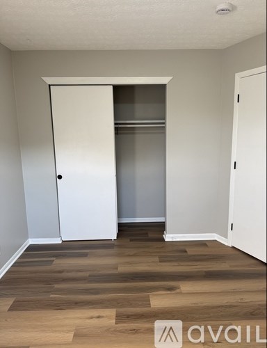 A room with a white door and wooden flooring.