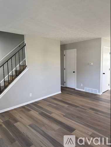A room with wooden flooring and a staircase with a railing.