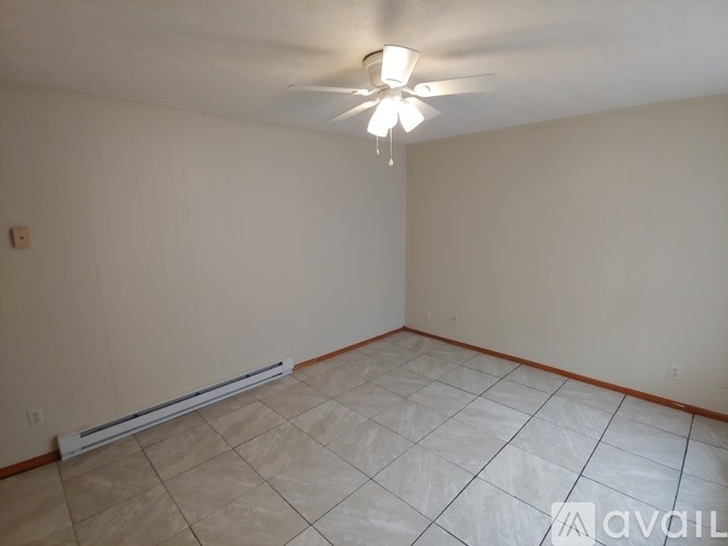 A room with a ceiling fan and tile flooring.
