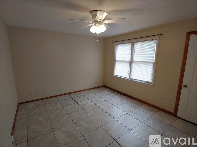 A room with a ceiling fan and a window with blinds.