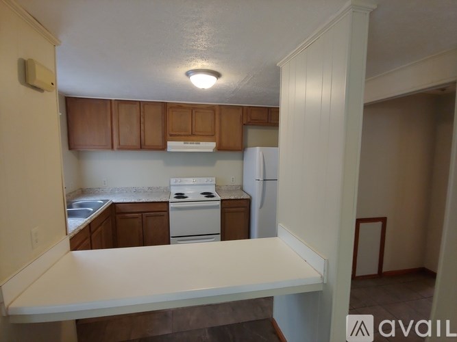 A kitchen with white appliances and wooden cabinets.
