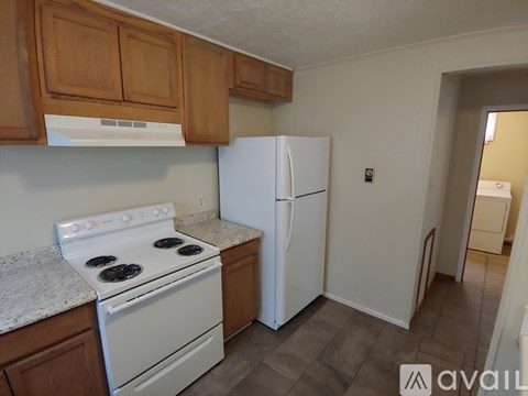 A kitchen with a white stove and refrigerator.