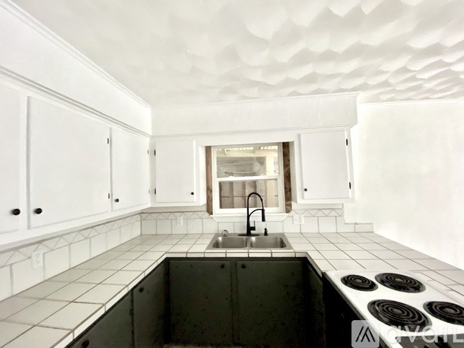 A kitchen with white cabinets and a black counter top.