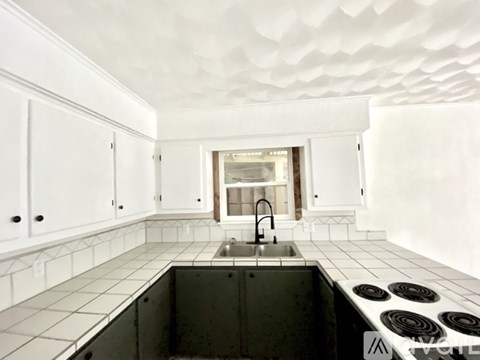 A kitchen with white cabinets and a black counter top.