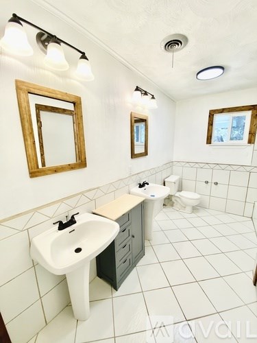 A white bathroom with a sink, mirror, and toilet.