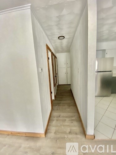 A long white hallway with a refrigerator on the right side.