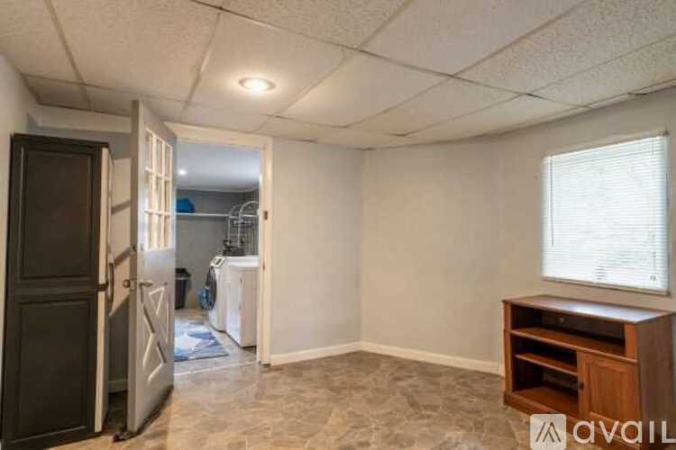 A kitchen area with a refrigerator, a cabinet, and a window.