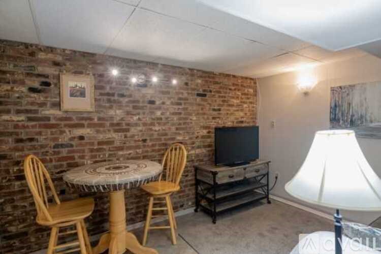 A room with a brick wall and a round table with chairs.
