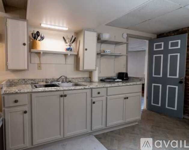 A kitchen with white cabinets and a marble countertop.