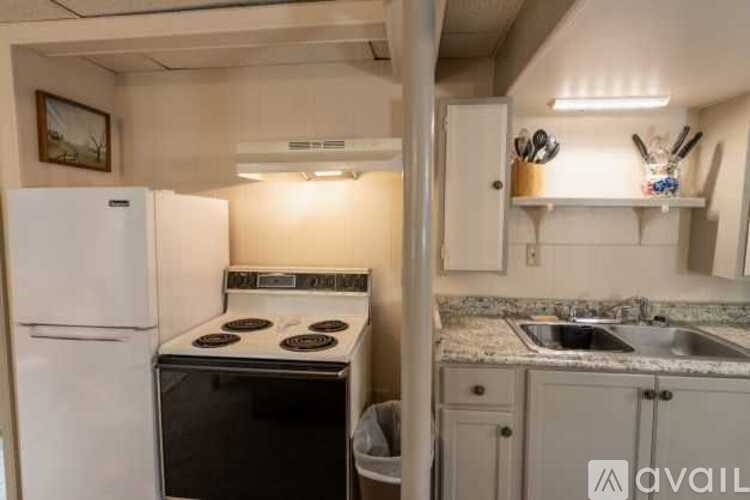 A small kitchen with a white refrigerator, stove, and sink.
