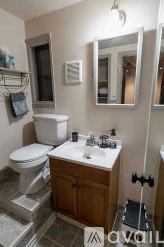 A bathroom with a toilet, sink, and mirror.